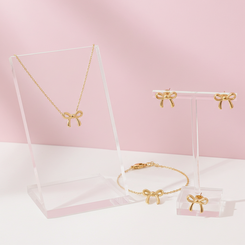 Gold jewelry set with bow accents on a pink background
